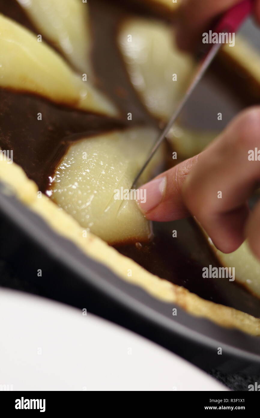 Chef cutting pears in chocolate filling with knife Stock Photo - Alamy