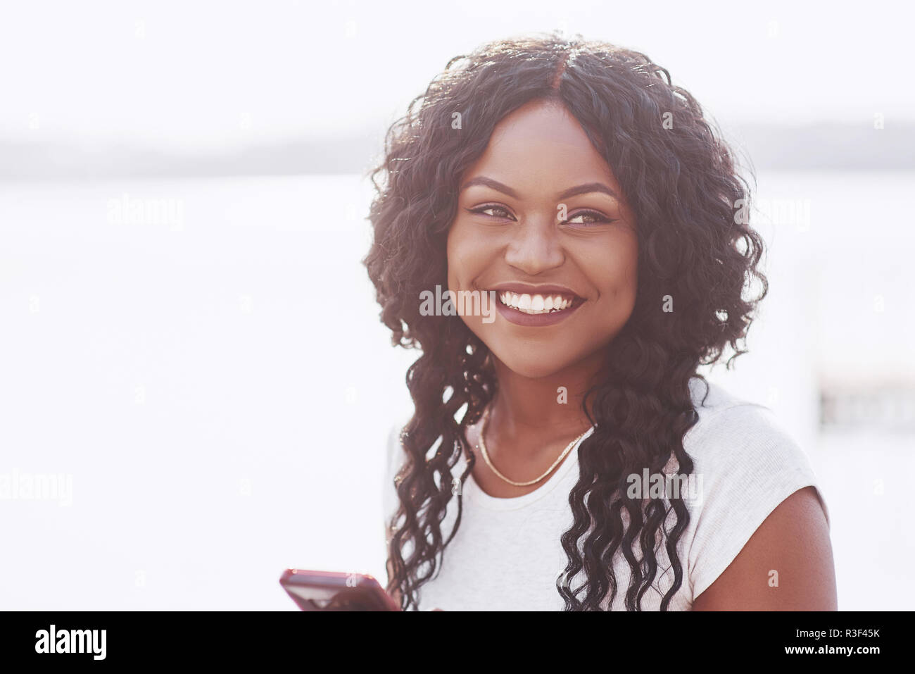 Portrait of smiling young black woman with sunlight flare Stock Photo ...