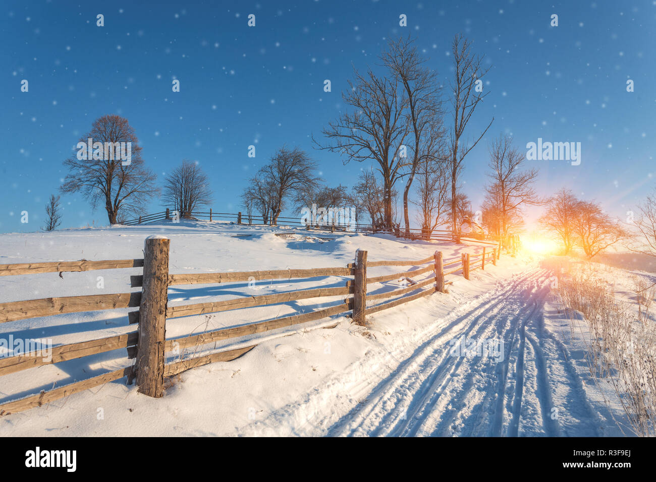 Winter country landscape with timber fence and snowy road into ...