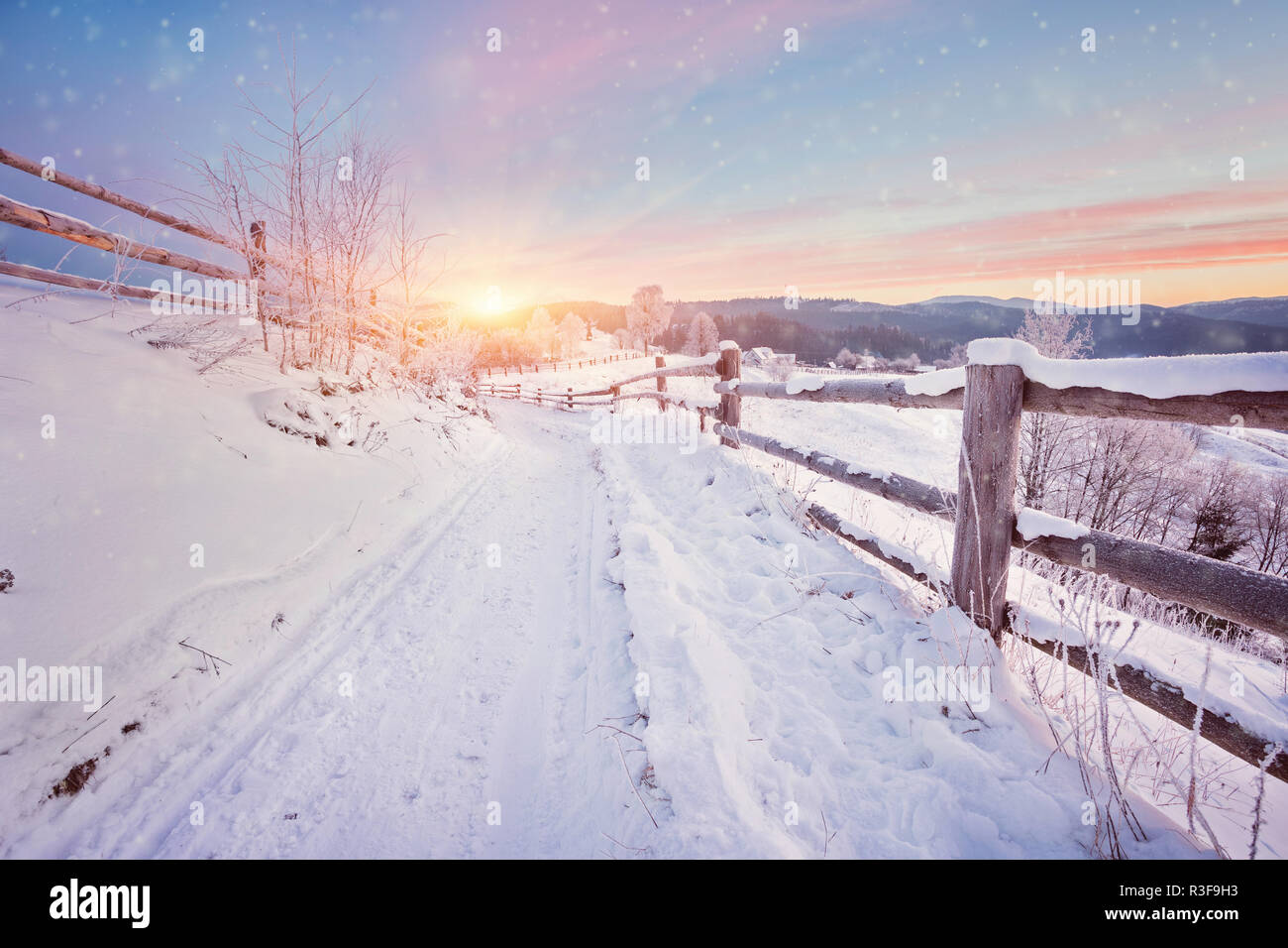 Winter country landscape with timber fence and snowy road into ...