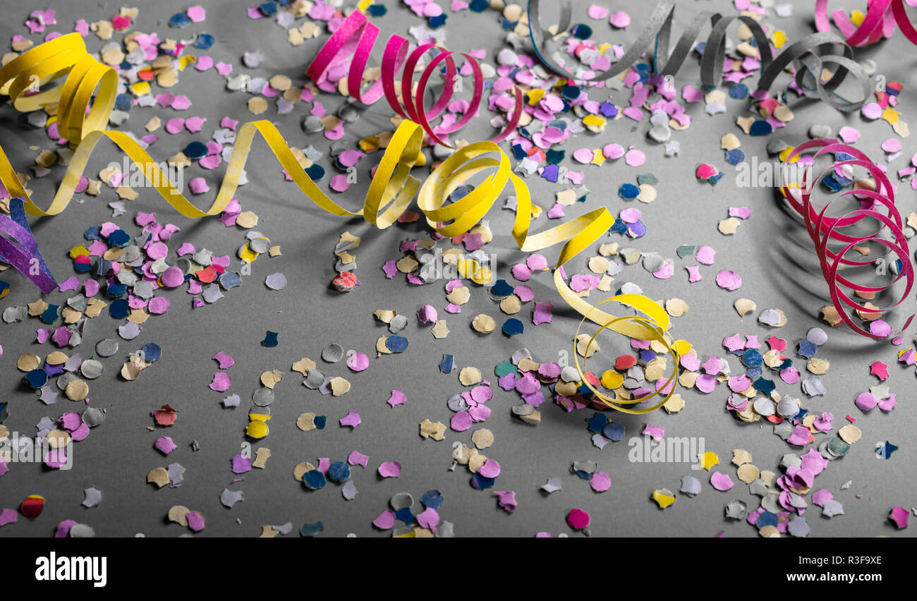 Carnival or birthday party. Confetti and serpentines on grey background Stock Photo