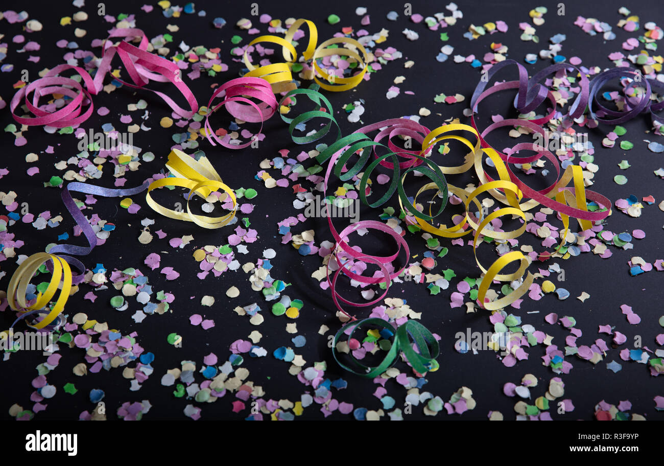 Carnival or birthday party. Confetti and serpentines on black background, top view Stock Photo