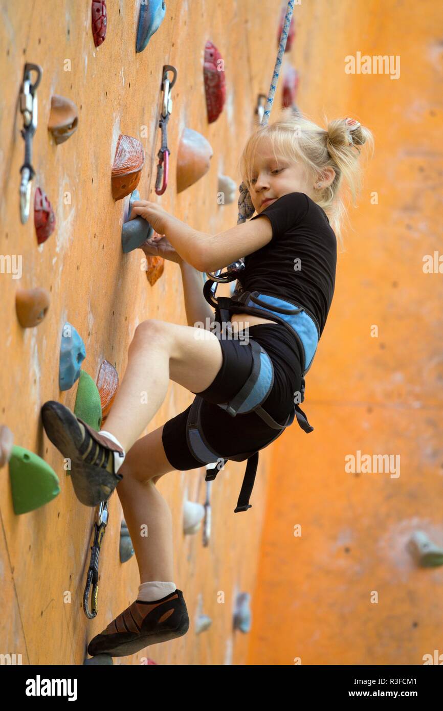 bouldering, little girl climbing up the wall and climber multicolored