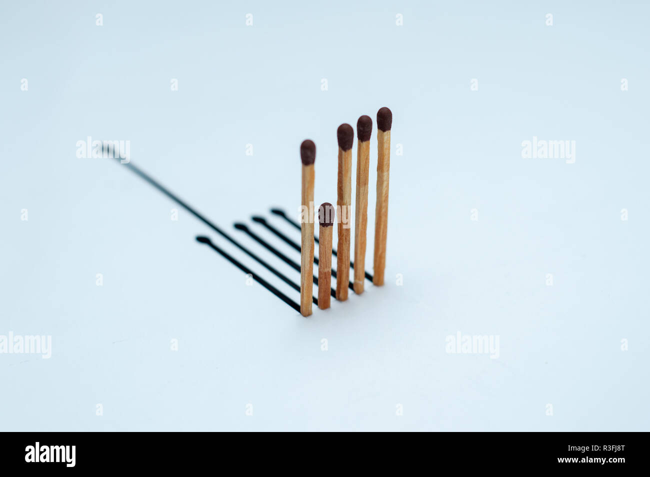 Wooden matches with the wrong shadow on white paper Stock Photo