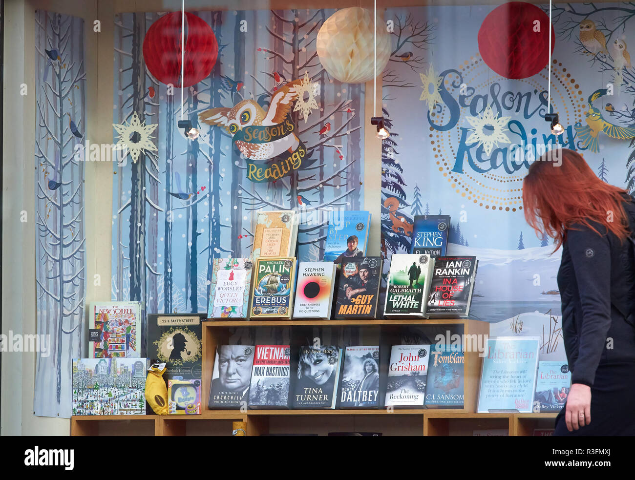 Display of books in a window with decorations for christmas time and a seasons reading