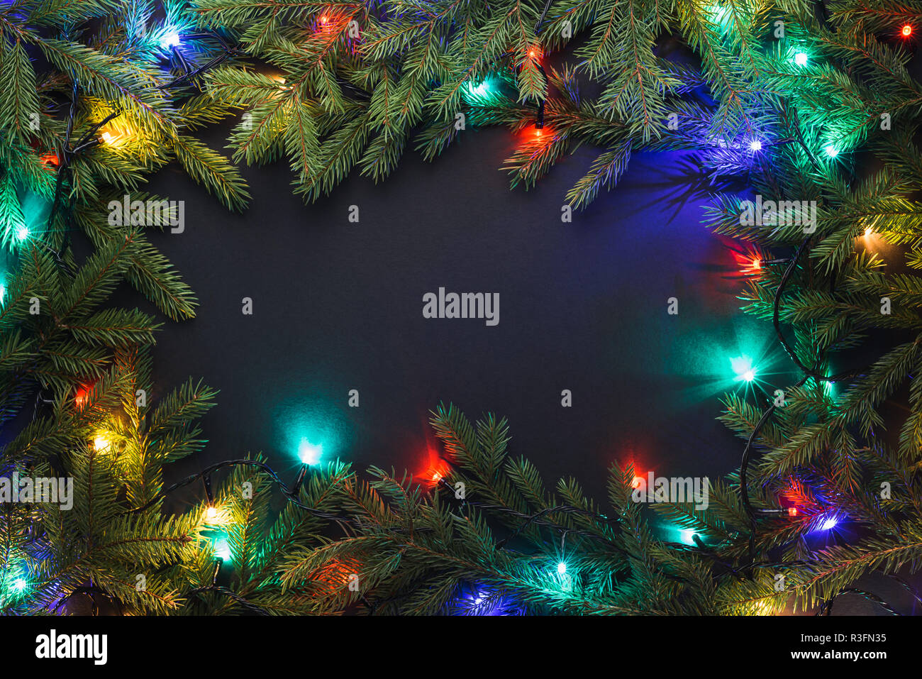 Christmas frame with fir branches and Christmas lights on black ...