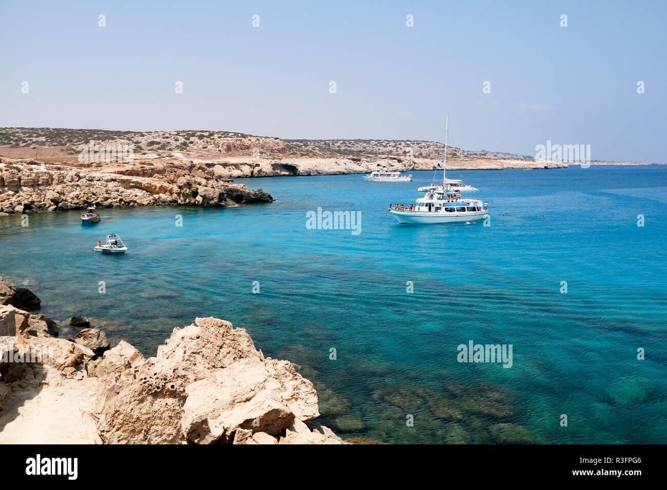 Pleasure boats exploring the clear blue waters at Cape Greco, Ayia Napa, Cyprus Stock Photo