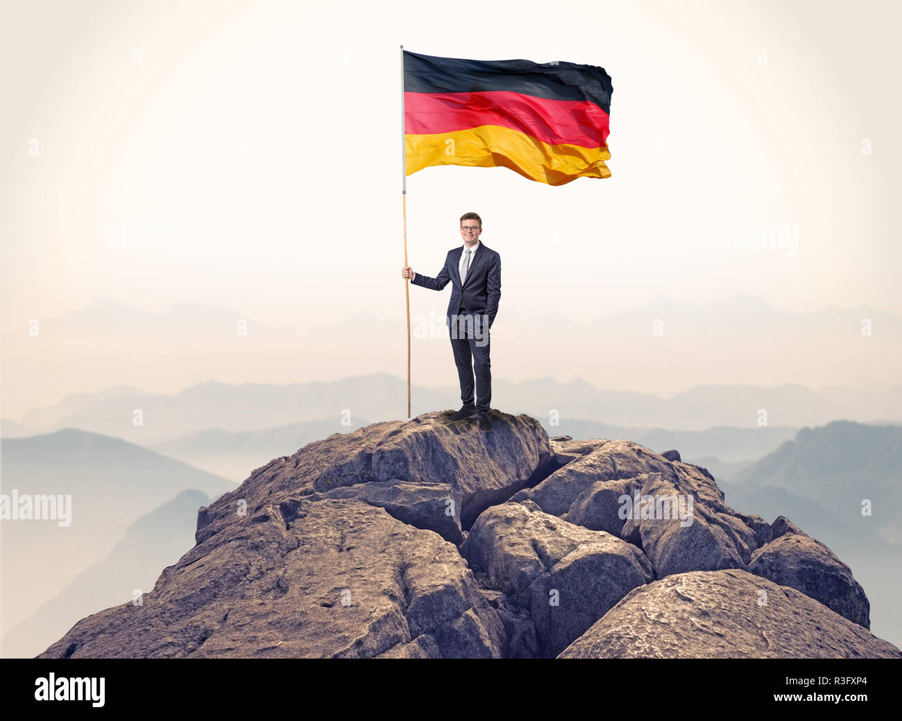 Successful businessman on the top of a mountain holding victory flag ...