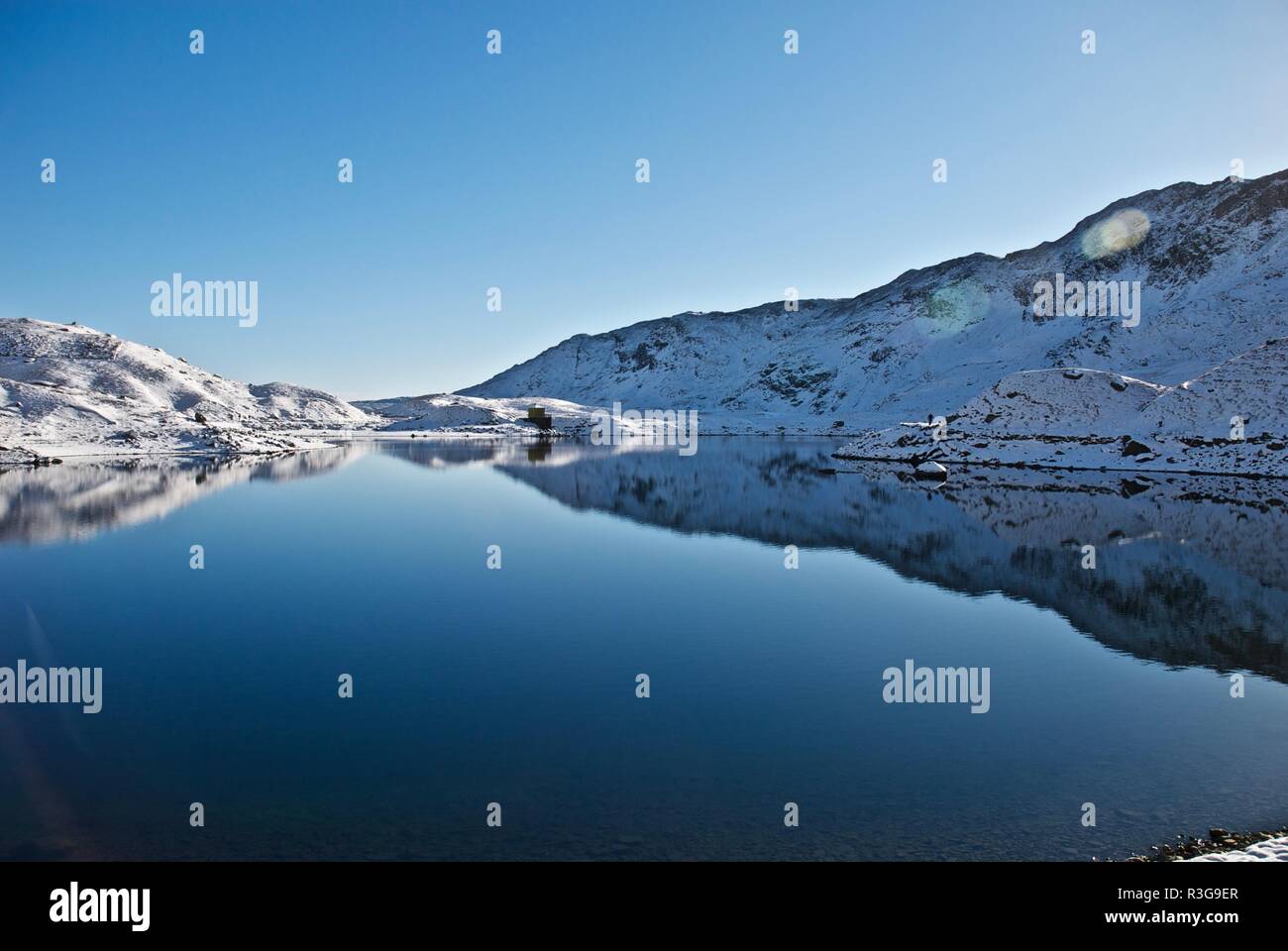 Snow covered hills reflected in a mountain lake, Mount Snowdon, Snowdonia National Park, Gwynedd, North Wales, UK Stock Photo