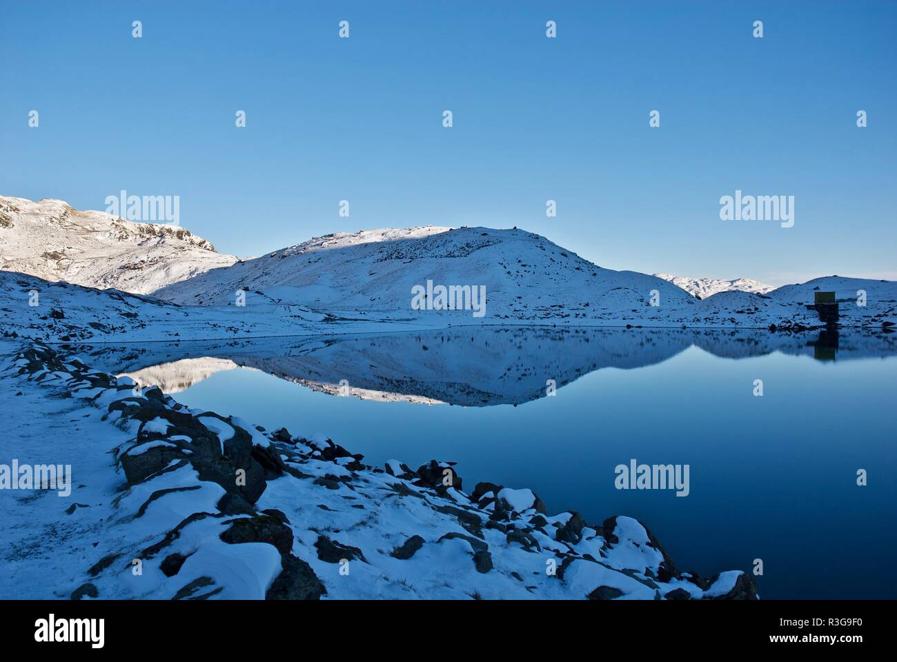 Snow covered hills reflected in a mountain lake, Mount Snowdon, Snowdonia National Park, Gwynedd, North Wales, UK Stock Photo