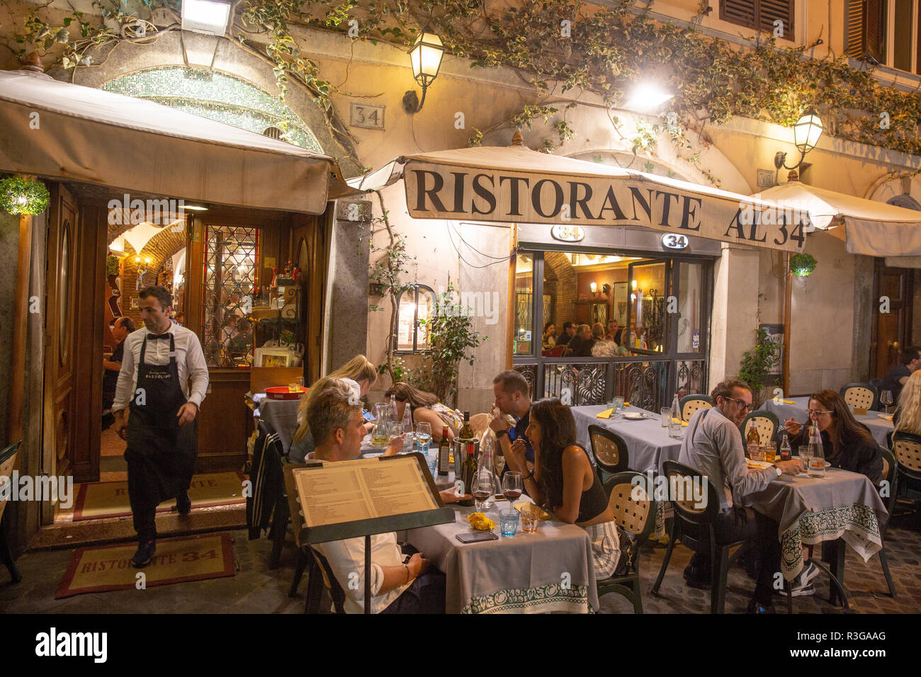 Traditional italian restaurant in Rome with diners eating dinner at night time in Rome,Italy Stock Photo