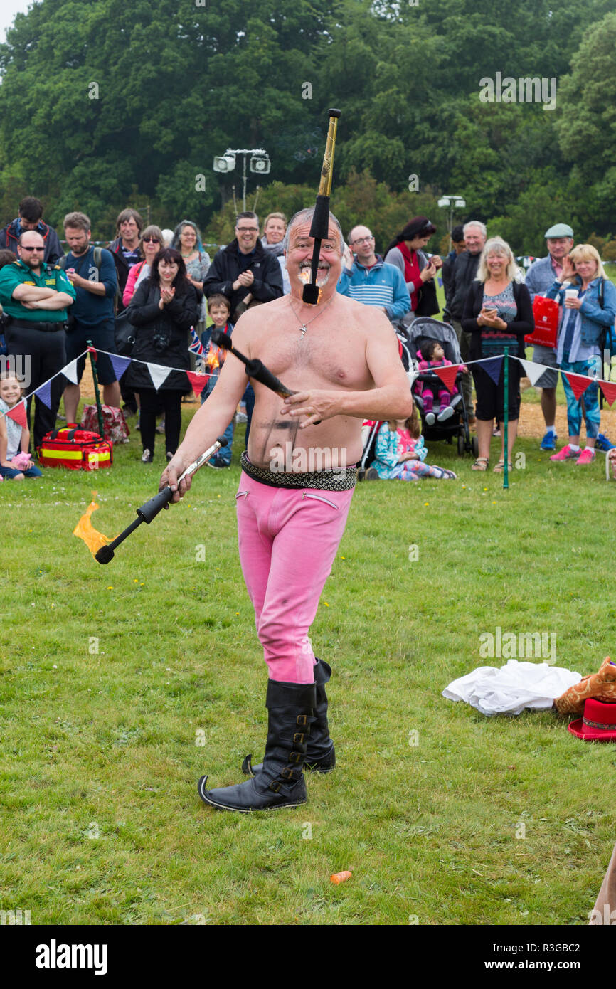 Juggler / performer with burning clubs / batons during a juggling with fire and fire eating display in front of an audience. England UK. (98) Stock Photo