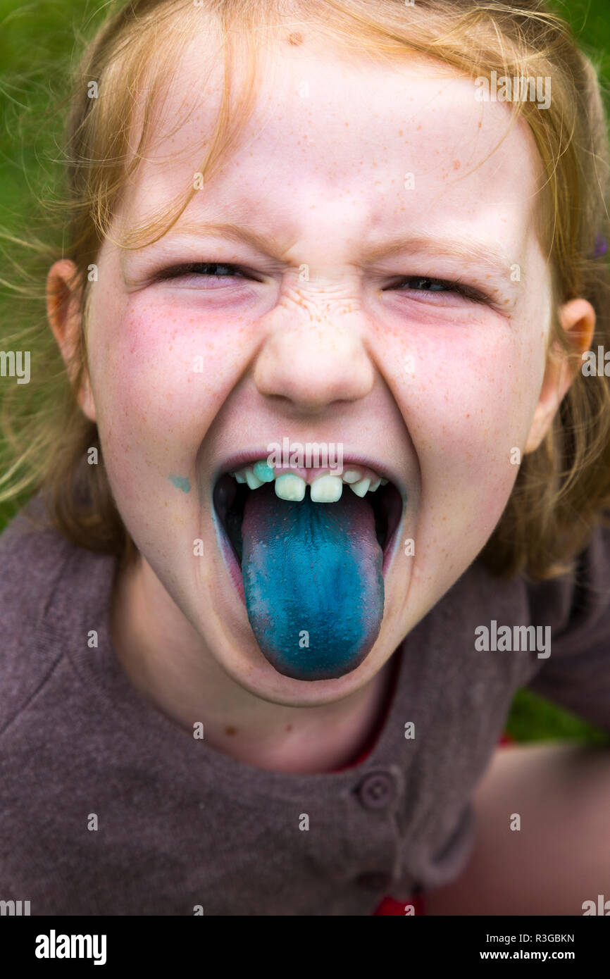 Eight year old girl eating / licking a blue ice lollipop / lolly pop