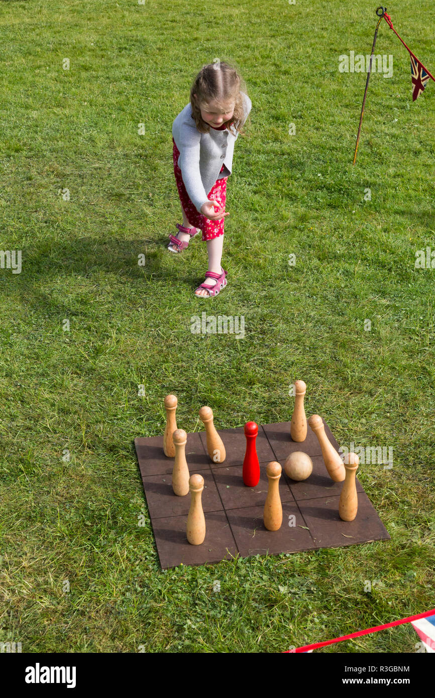 A six year old girl playing with an old-fashioned traditional classic set of skittles on a board requiring the throwing of a ball by players. UK (98) Stock Photo