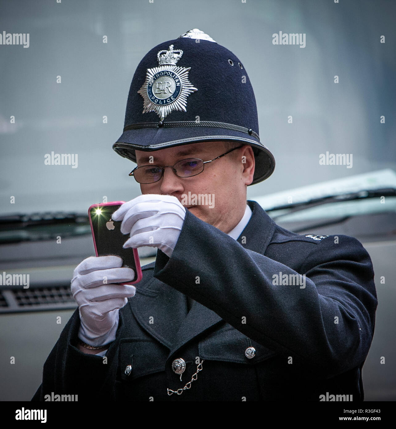 A London Policeman taking a photo with his mobile phone Stock Photo