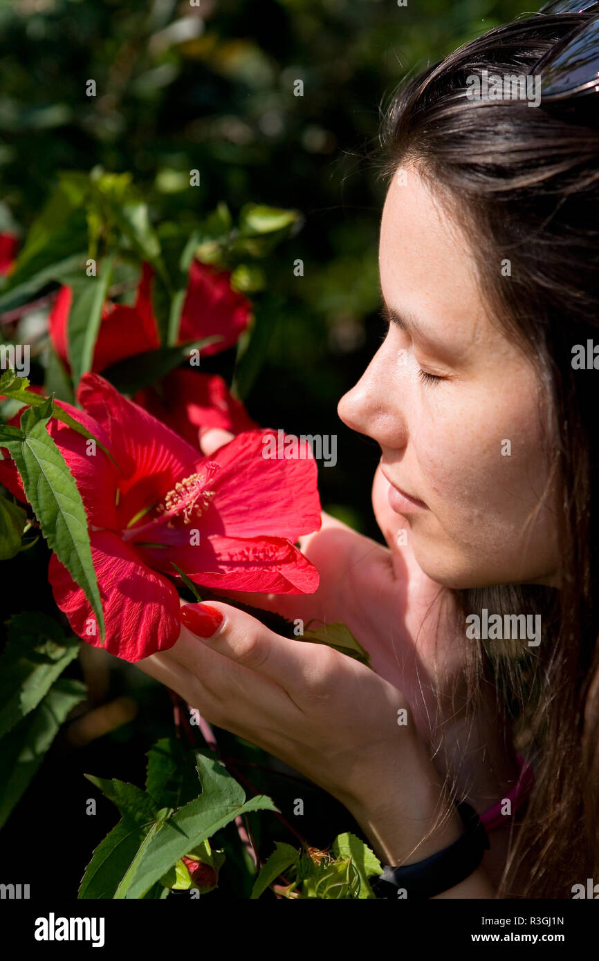 The girl smells a red flower. Human and nature Stock Photo - Alamy
