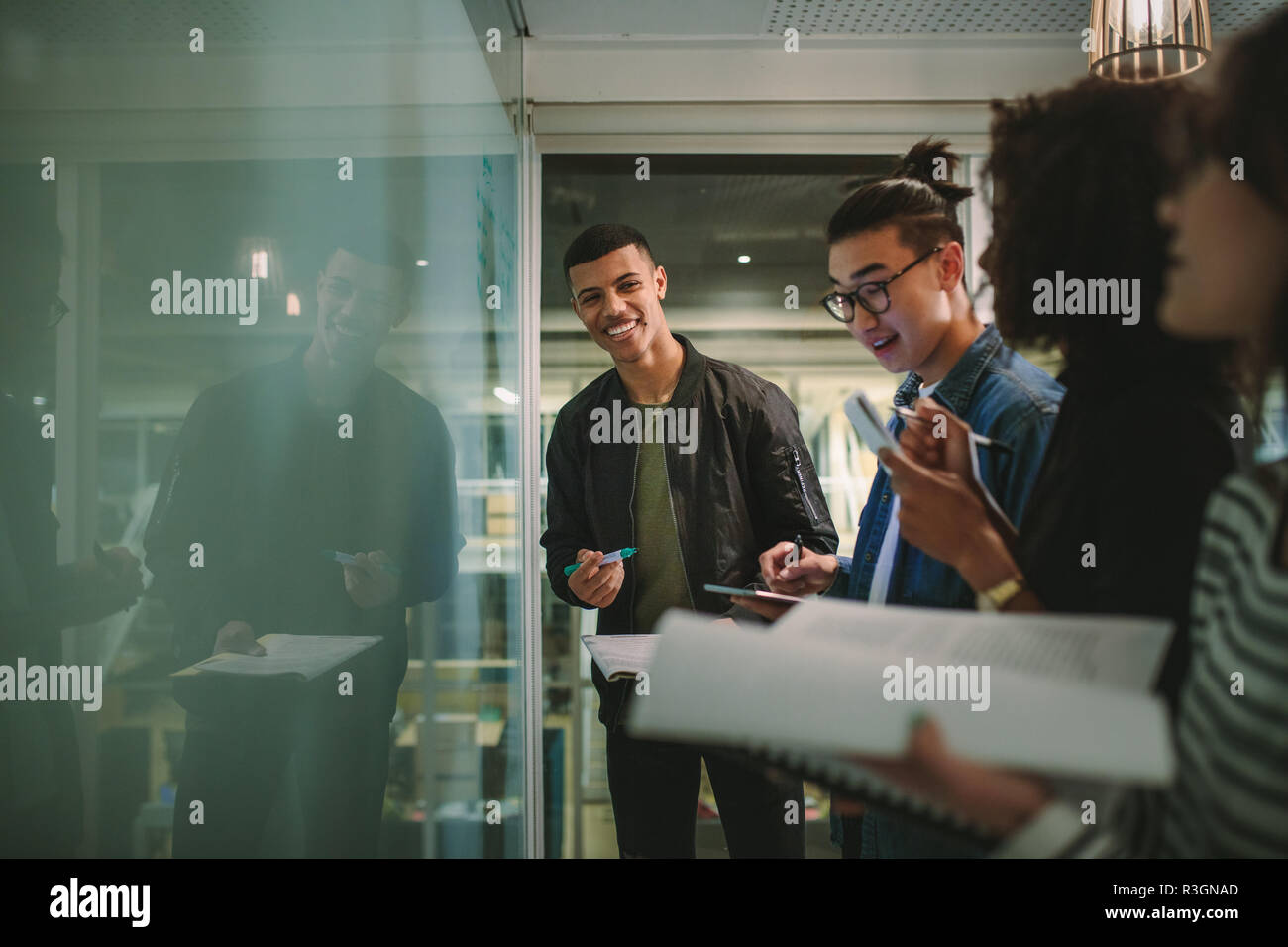 Group of students standing together at blackboard with books. Multi-ethnic university students during workshop. Stock Photo