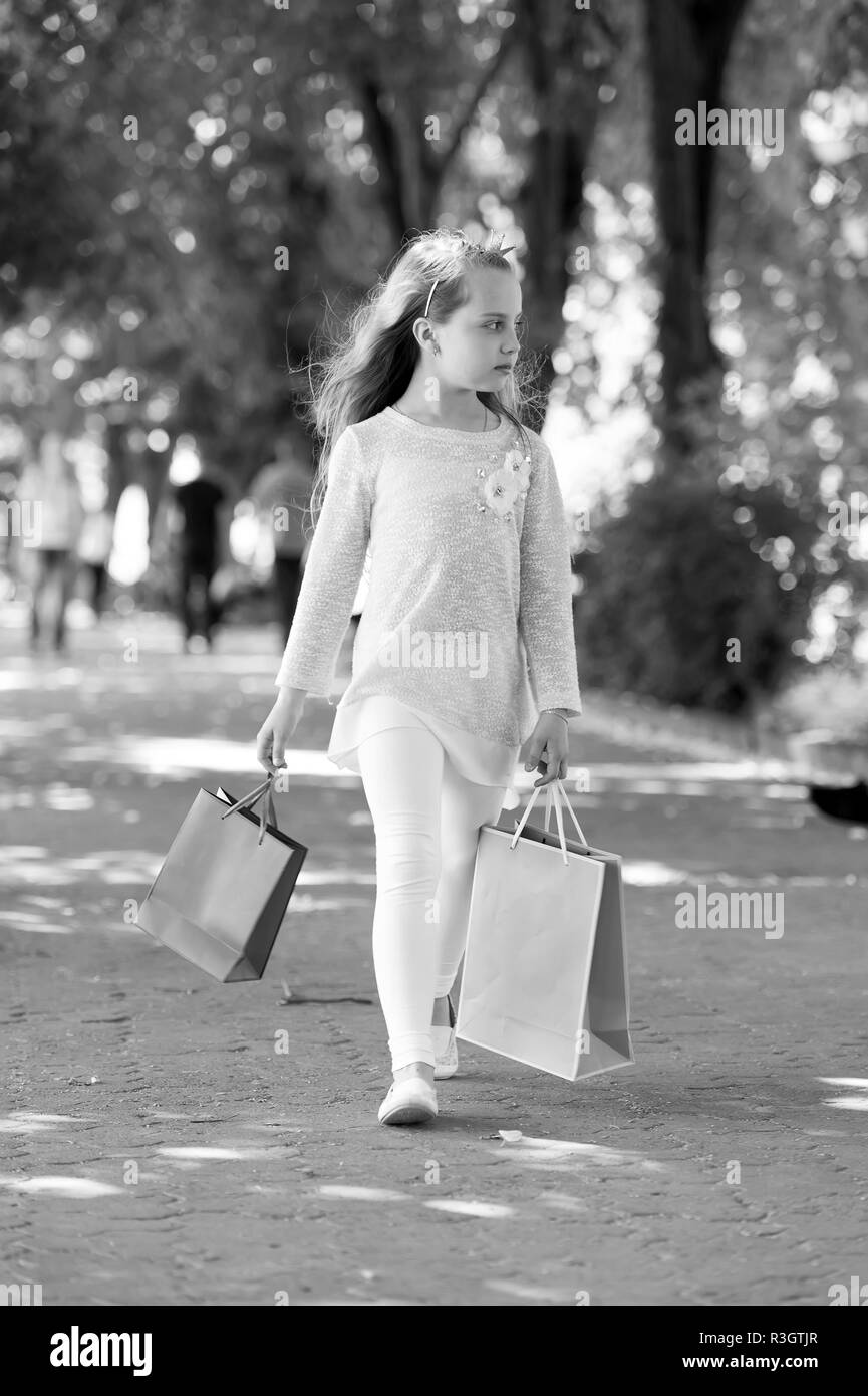 Shopping on sale and purchase. Kid shopper in fashion clothes outdoor. Girl with shopping bags walk in park. Child with paper bags in summer. Little p Stock Photo