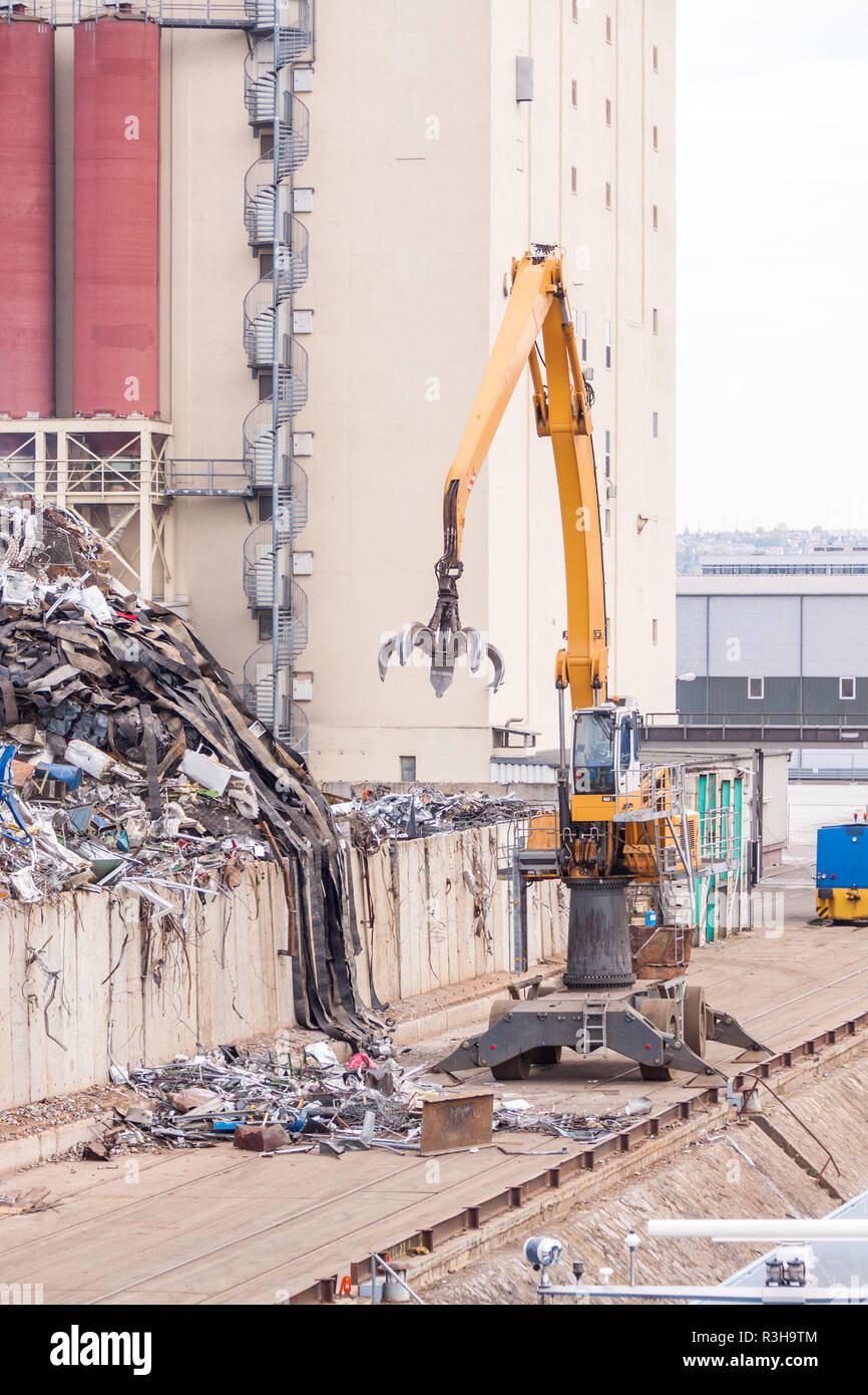 duty crane with scrap metal discharges onto a cargo ship at dock Stock ...
