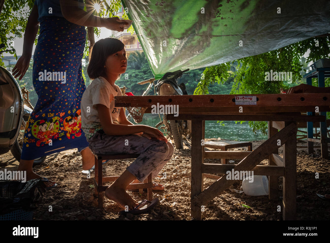 Burmese girl sitting outside at a riverside cafe, Mandalay, Myanmar. Stock Photo