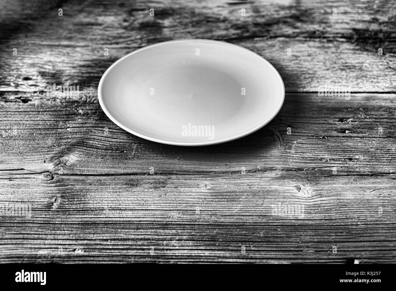 Black and white photo . Blue empty dish on a wooden table. Rustic style, home cooking. Stock Photo