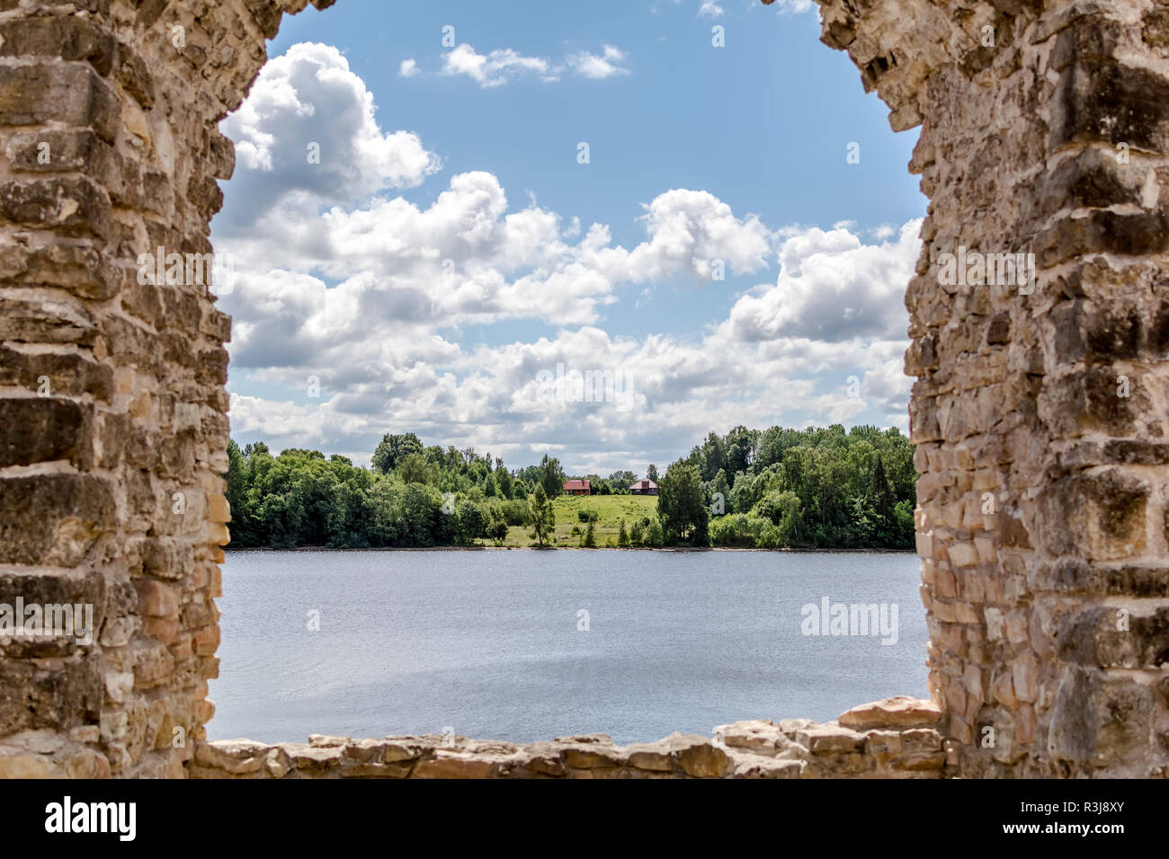 View to the rural cottage at river bank through ruins of Koknese Castle - one of the largest and most significant medieval castles on Latvian territor Stock Photo