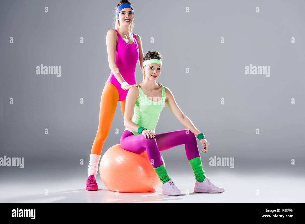 athletic young women in 80s style sportswear smiling at camera on grey Stock  Photo - Alamy
