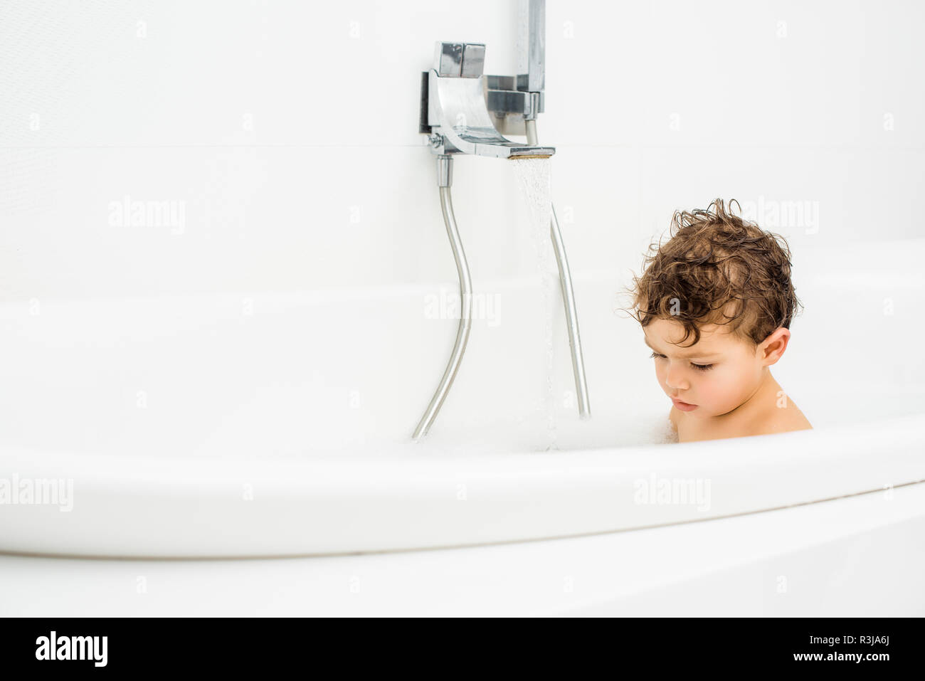Toddler boy sitting in bathroom with running water Stock Photo Alamy