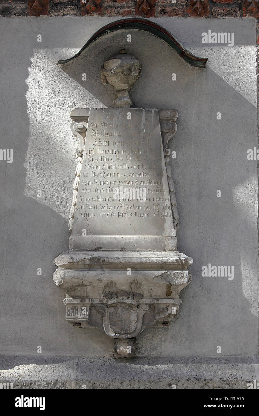 On the outside walls of the Frauenkirche in Munich, are situated a collection of wall-mounted ancient tombstones/headstones, as viewed here. Stock Photo