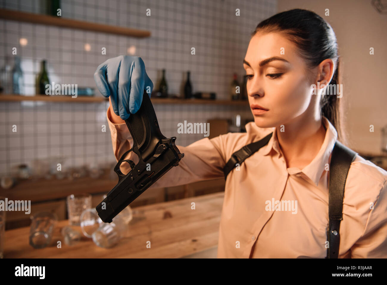 close up of female detective in gloves investigating gun at crime scene