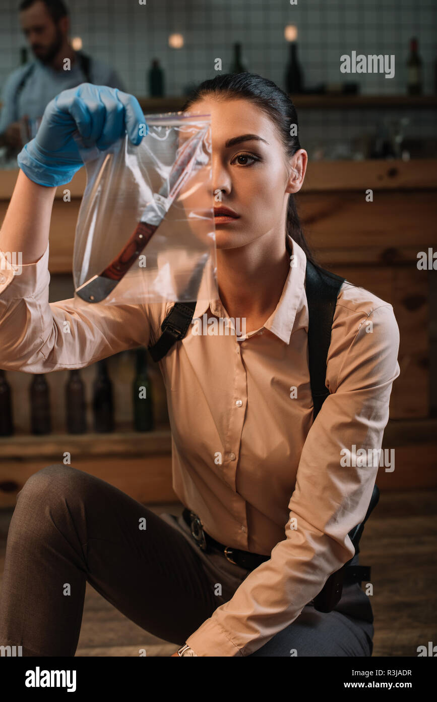 focused female detective looking at evidence at crime scene Stock Photo