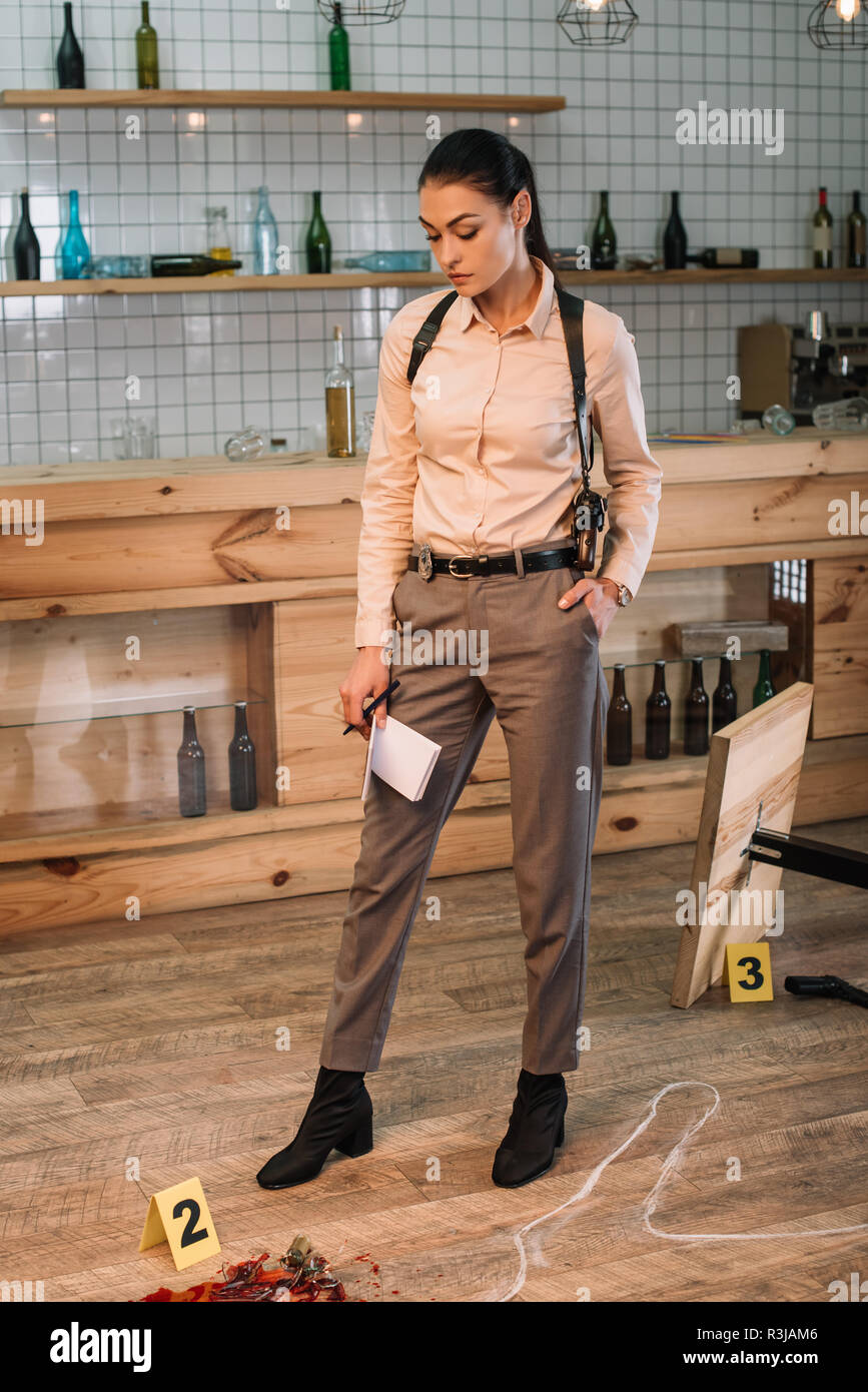 serious female detective investigating evidence at crime scene Stock