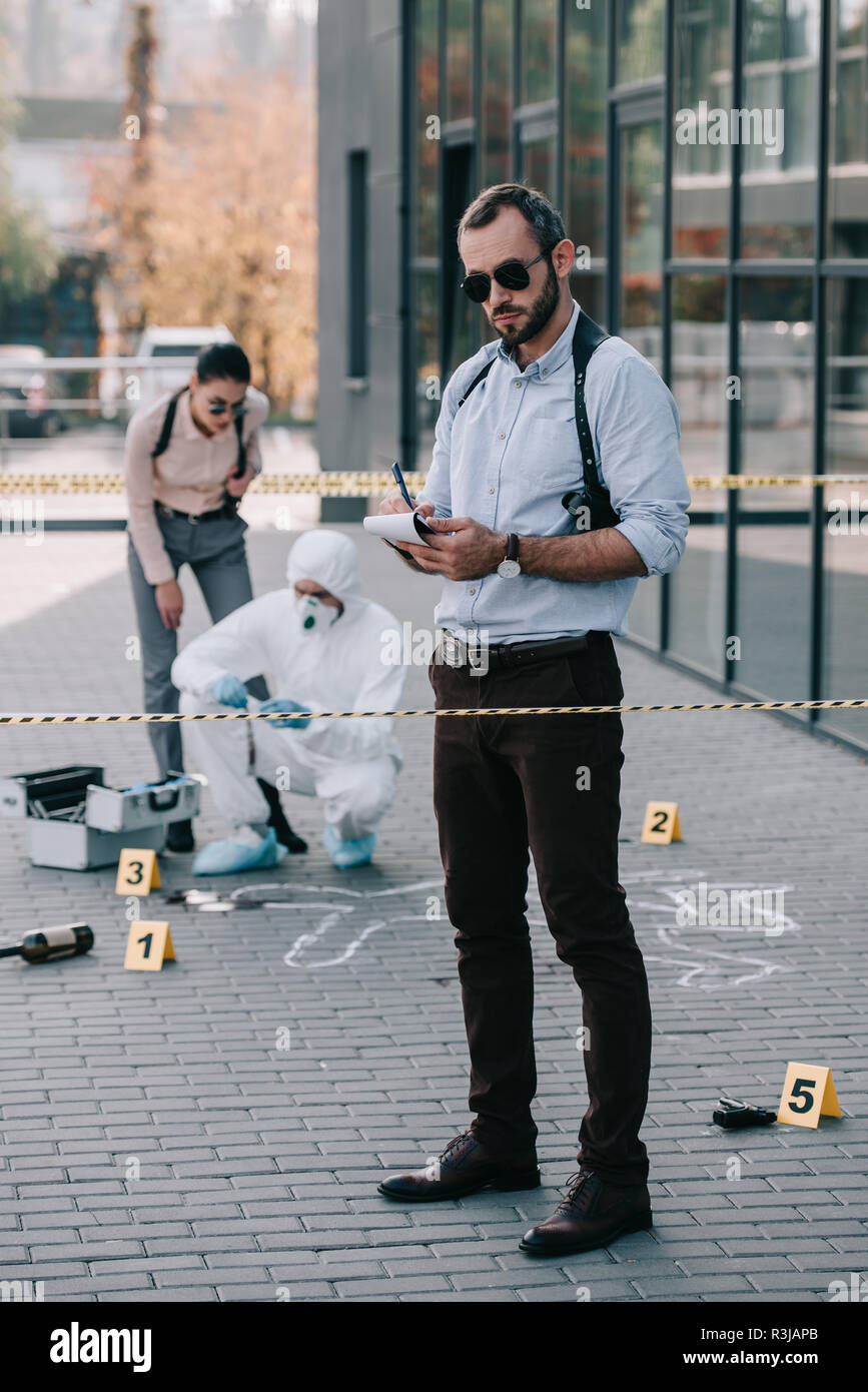 male detective standing at crime scene and making some notes Stock
