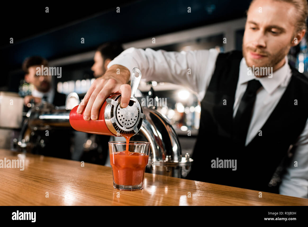Barman pouring drink in glass on wooden counter Stock Photo