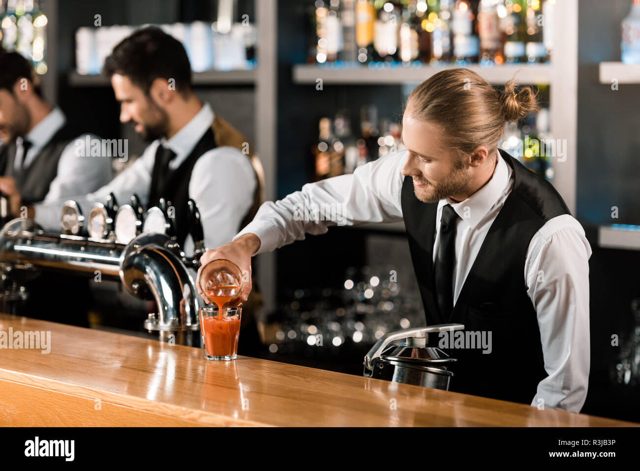 Barman pouring drink in glass on wooden counter Stock Photo