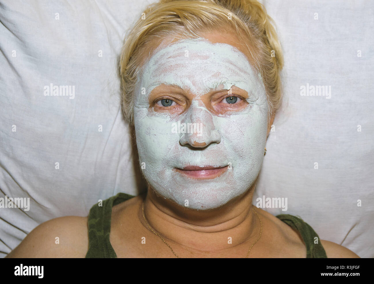 Aged woman with a cosmetic mask on face at home - beauty treatments concept. Stock Photo