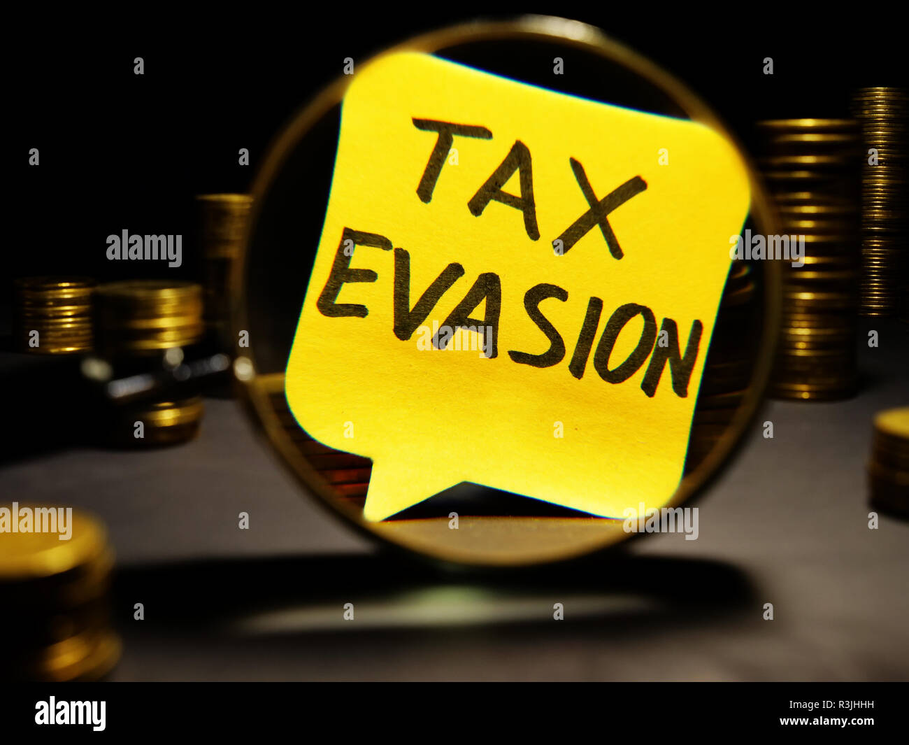 Magnifying glass and words tax evasion with money. Stock Photo