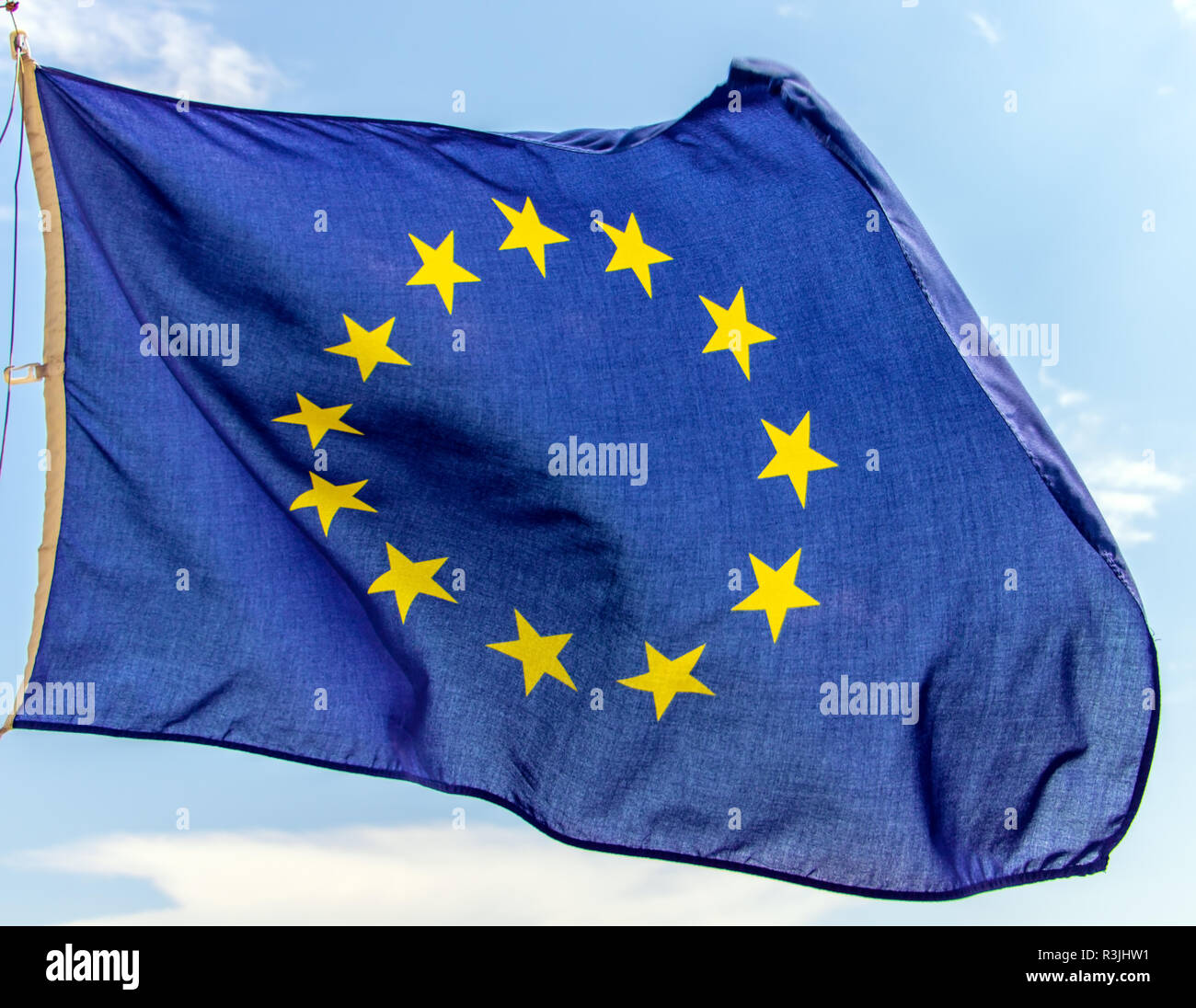 Flag of the European Union flutters on the blue sky. A blue flag with ...