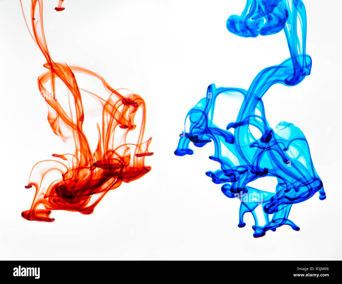 Food coloring dropped into glass of water and dispersing. Stock Photo