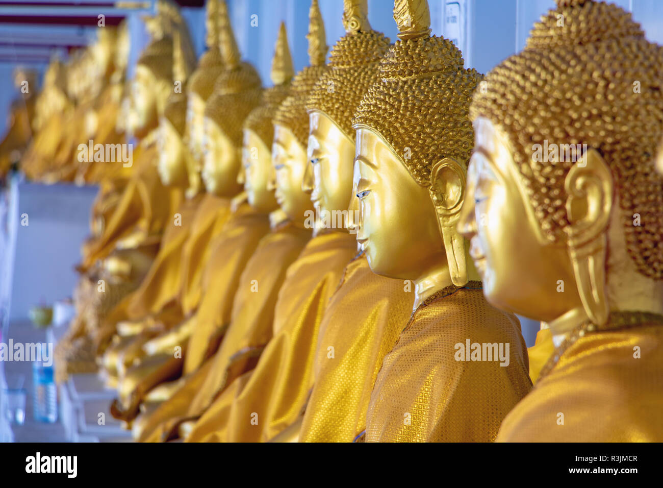 A long line of golden statues of the Buddha at Buddhist temple in ...