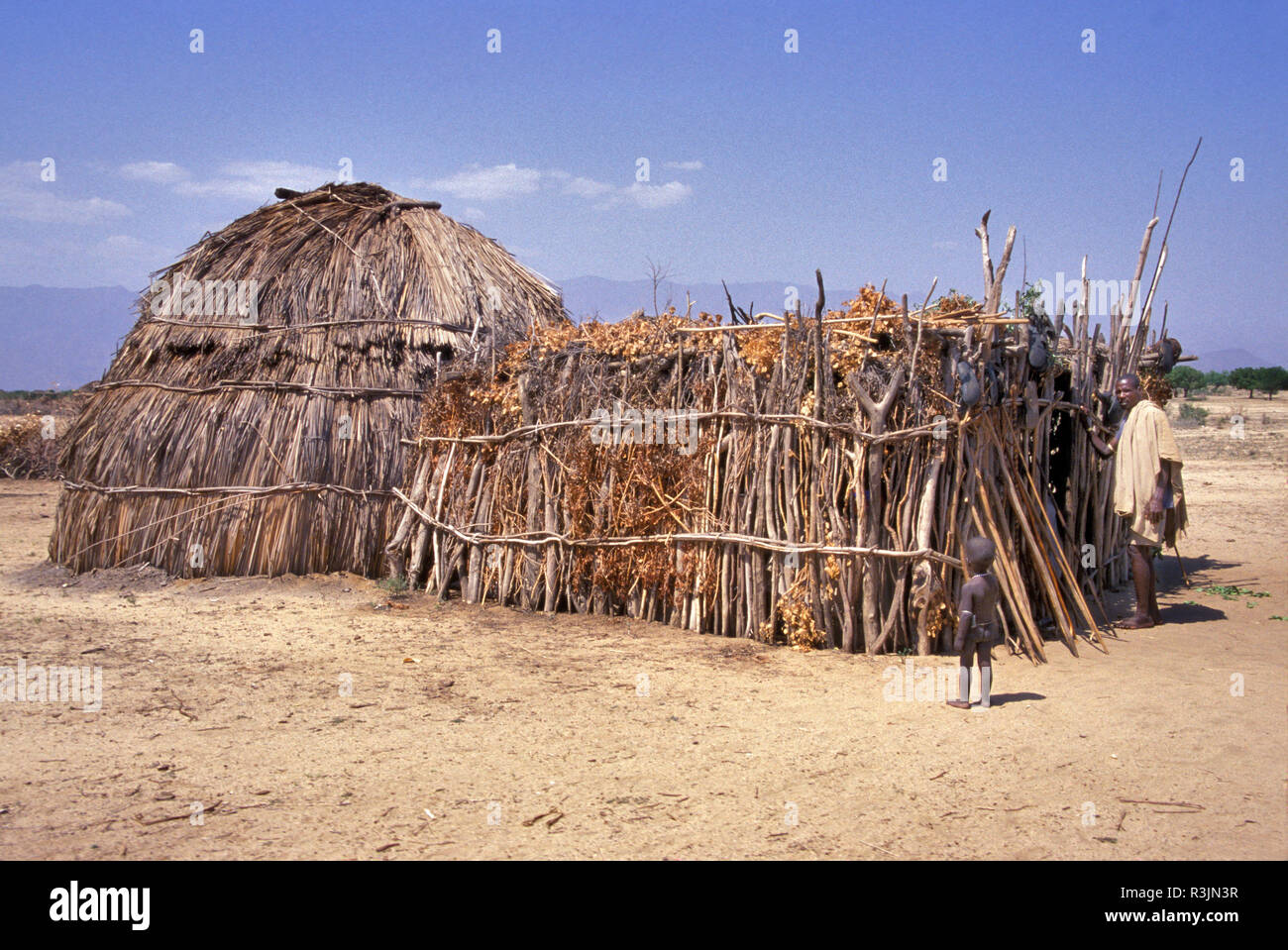 Africa, Ethiopia, Omo region. A small child stands by a typical stick and grass Aerbora tribe house. Stock Photo