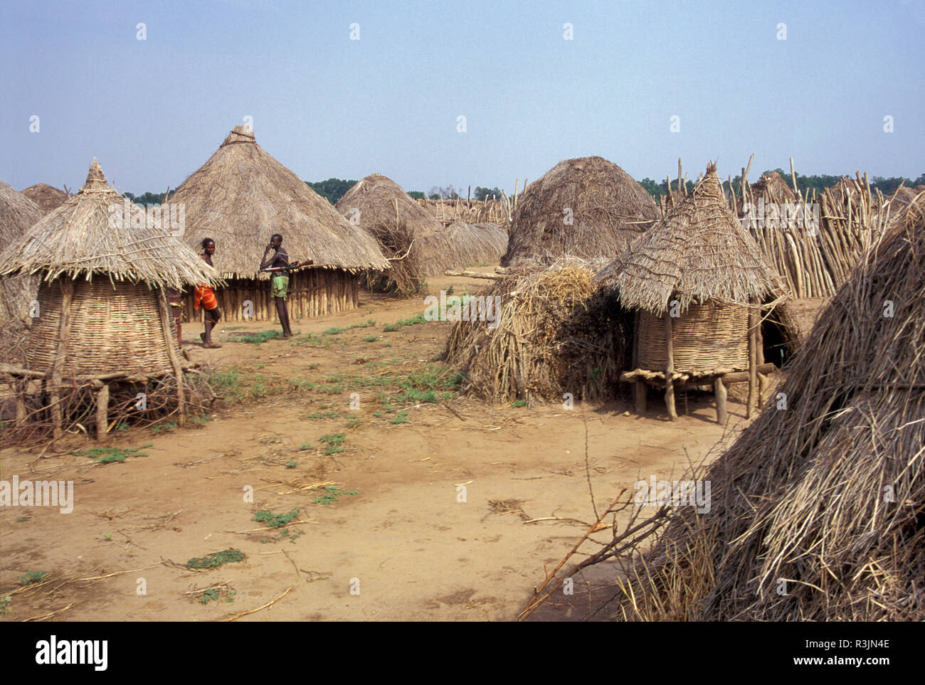Africa, Ethiopia, Omo region. Two guys with guns standing among thatched buildings in Doose (Dooze), the largest of the Karo tribe villages. Stock Photo
