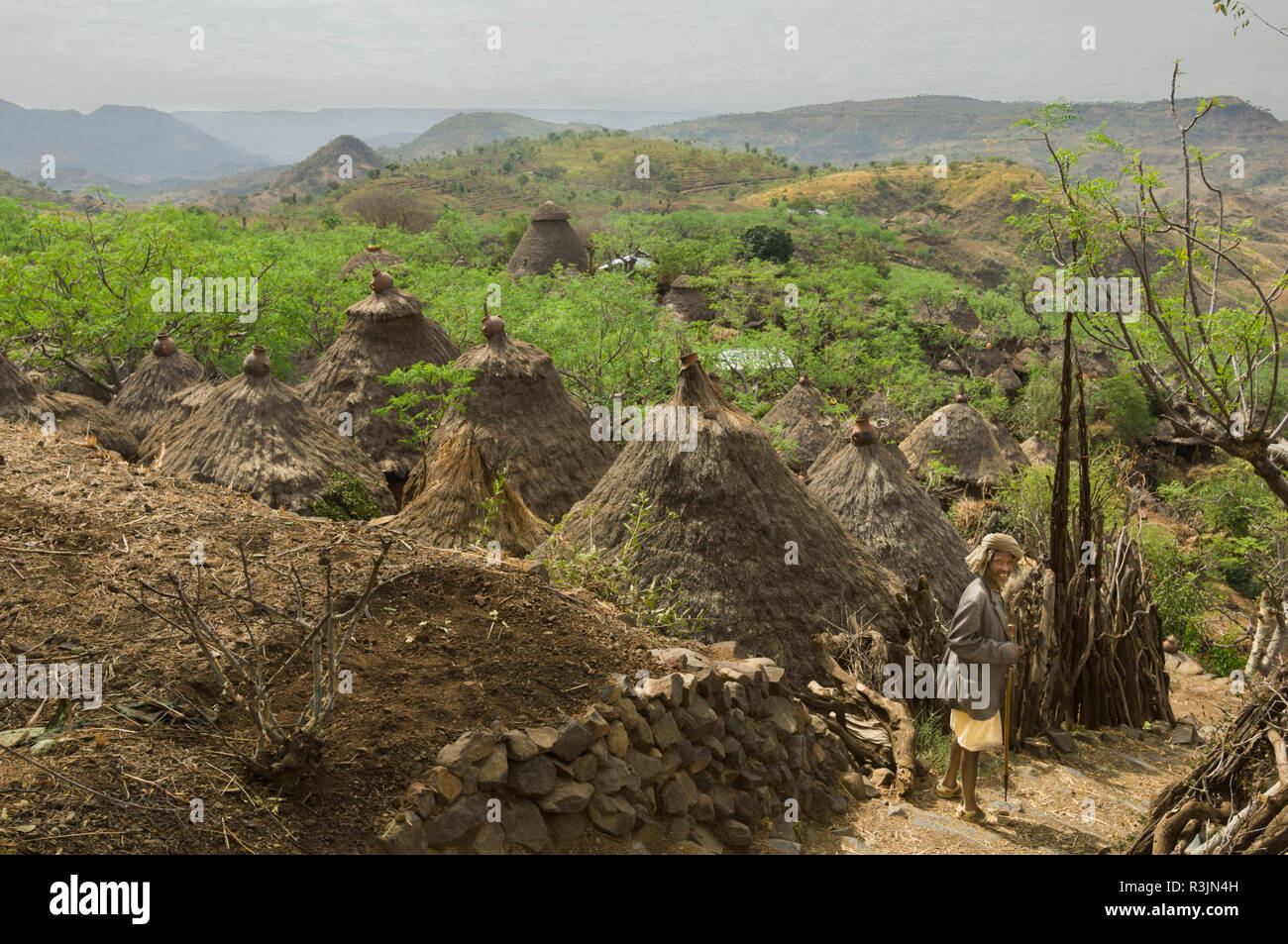 Africa, Ethiopia, Omo region. An old man on a path next to some thatched buildings in the Konso tribe village of Busso. Stock Photo