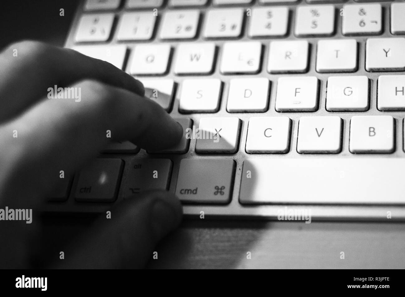 Black and white hand on apple MAC keyboard Stock Photo
