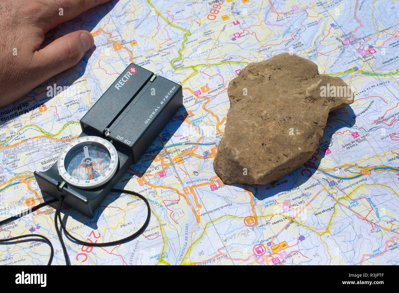 Map, witchcraft and hand of an explorer orientation on the ground Stock Photo