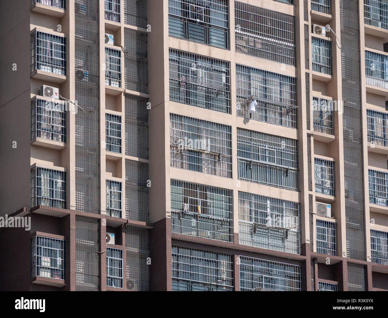 Facade of high-rise apartment building. Exterior of high-density residential building with most windows secured with burglar mesh. Liuzhou, China. Stock Photo