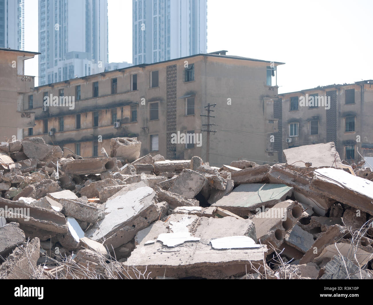 Rubble of destroyed/demolished brick buildings against some old residential apartment buildings in distance. Liuzhou China Stock Photo