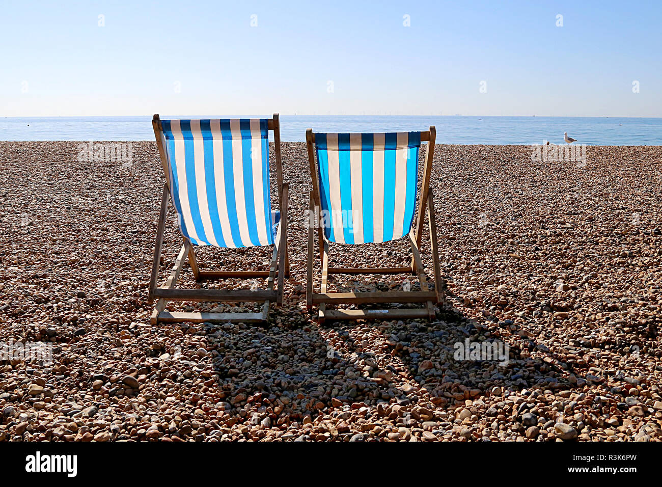 Two Empty Deckchairs and a Seagull on Brighton Beach. UK Stock Photo