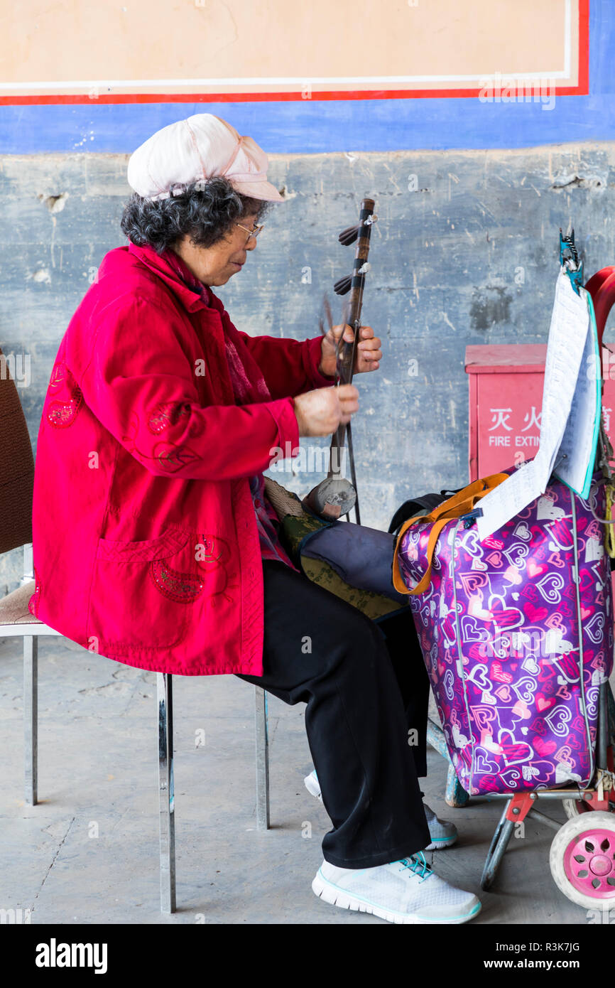 Asia, China, Beijing, Forbidden City, Back Hall, Ancestral Shrine. Woman playing an erhu or Chinese violin on the porch of the Ancestral Shrine. Stock Photo