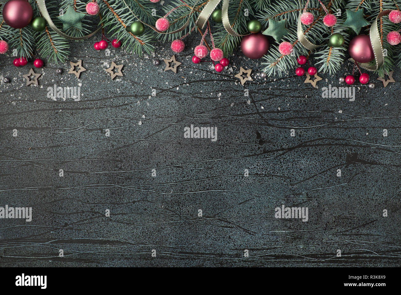 Christmas background with green fir twigs, red berries and candy canes on textured dark board text space Stock Photo